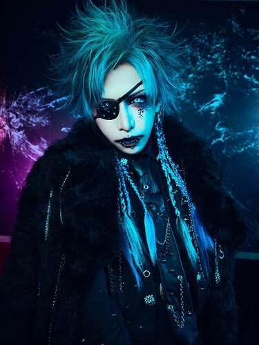 Greyish hair, with braided extensions at the back, dark vibe eye make-up and lipstick, dark eyepatch, a few small black rhinestones under the other eye, several facial piercings, dark clothes, black leather necktie with chains, furry like black jacket put over his shoulders.