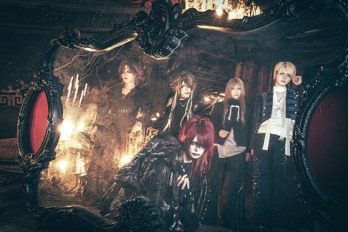Picture of the band taken through a mirror, standing in the back next to each other from left to right Ryohei, S1TK, Ryu, Shiyu, in the front, crouching, Ryo.